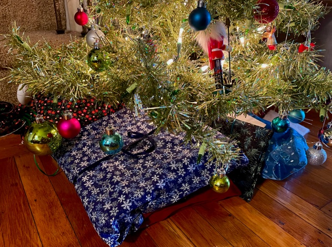 gifts in reusable cloth bags under a Christmas tree