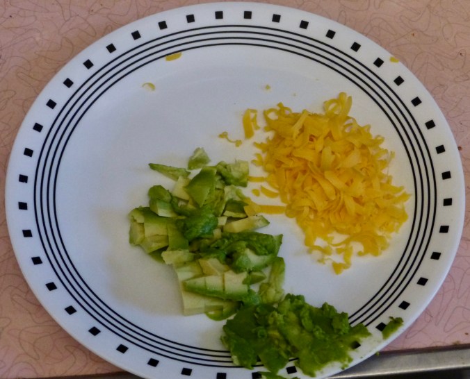 grated cheddar and diced avocado on plate