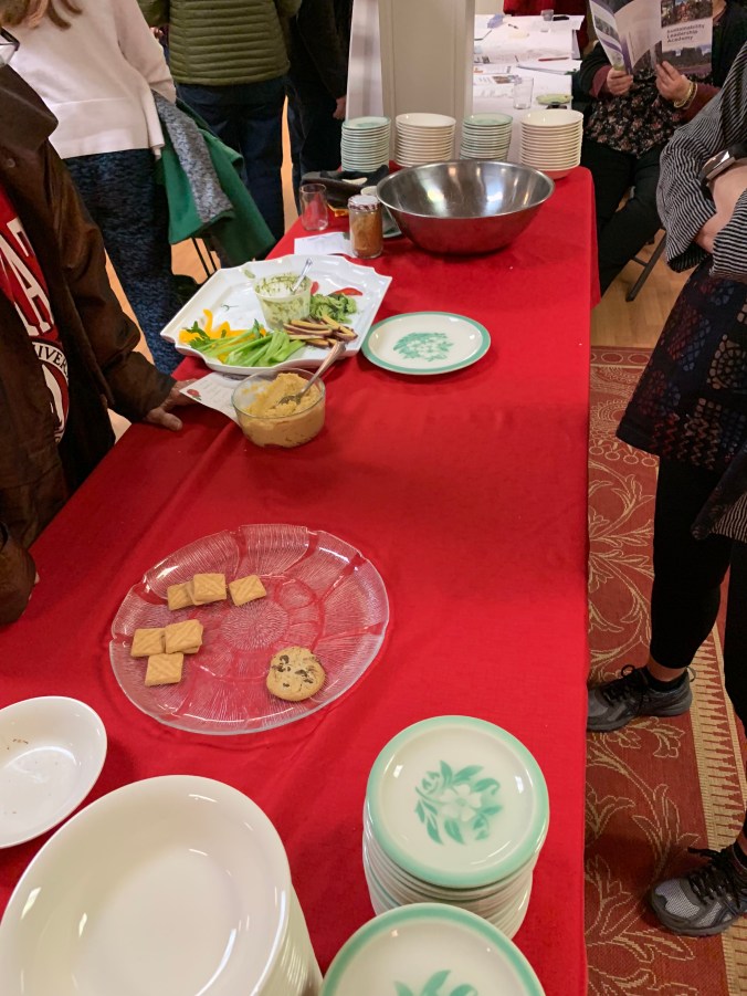buffet with mostly-empty plates of vegetables and cookies and popcorn