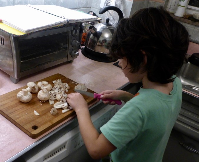 Five-year-old slicing mushrooms with paring knife