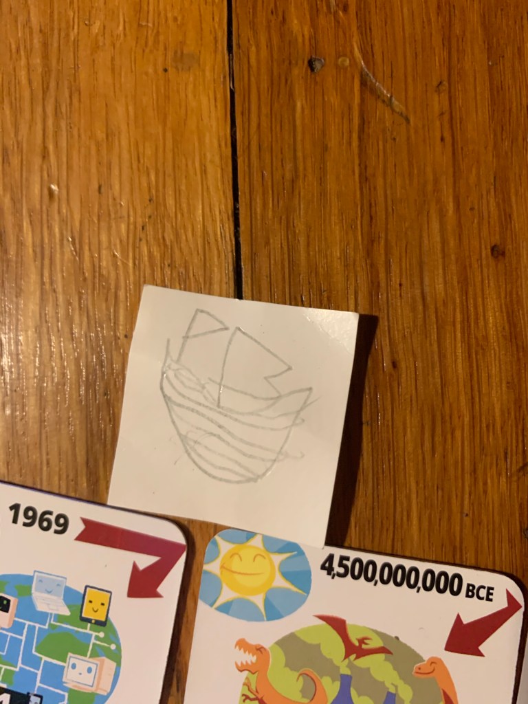 A small square of paper with a child's drawing of a ship, placed next to Time Breaker tiles.